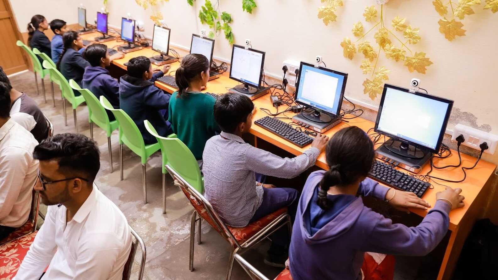 Students learning computer skills in a decorated lab with modern PCs and educational tools.